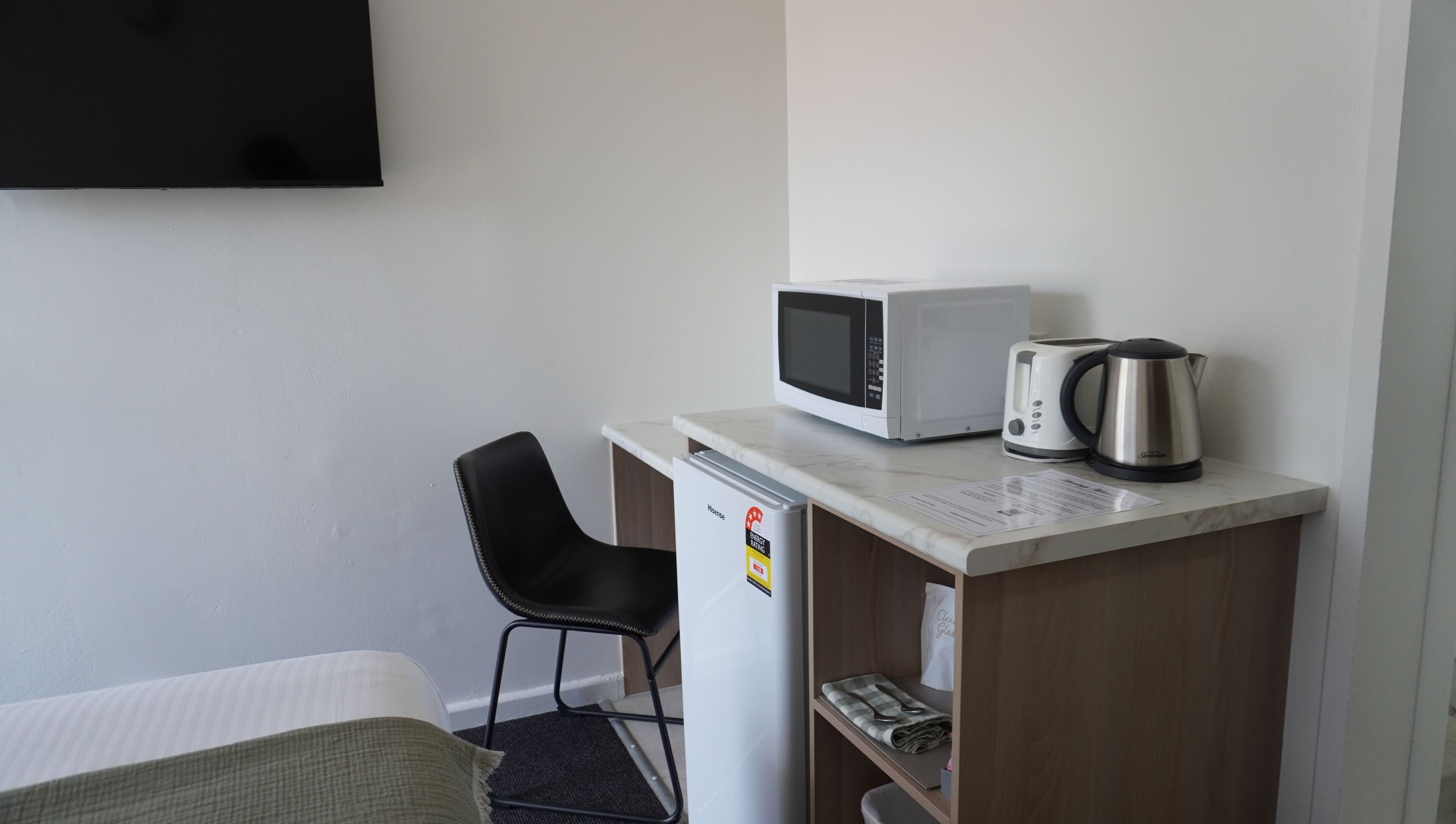 A compact hotel room with a kitchenette, including a microwave, toaster, and coffee maker.