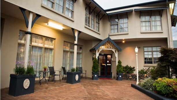 A hotel with a covered patio area, outdoor seating, and a well-lit entrance. - Abbotsleigh Motor Inn (Armidale)