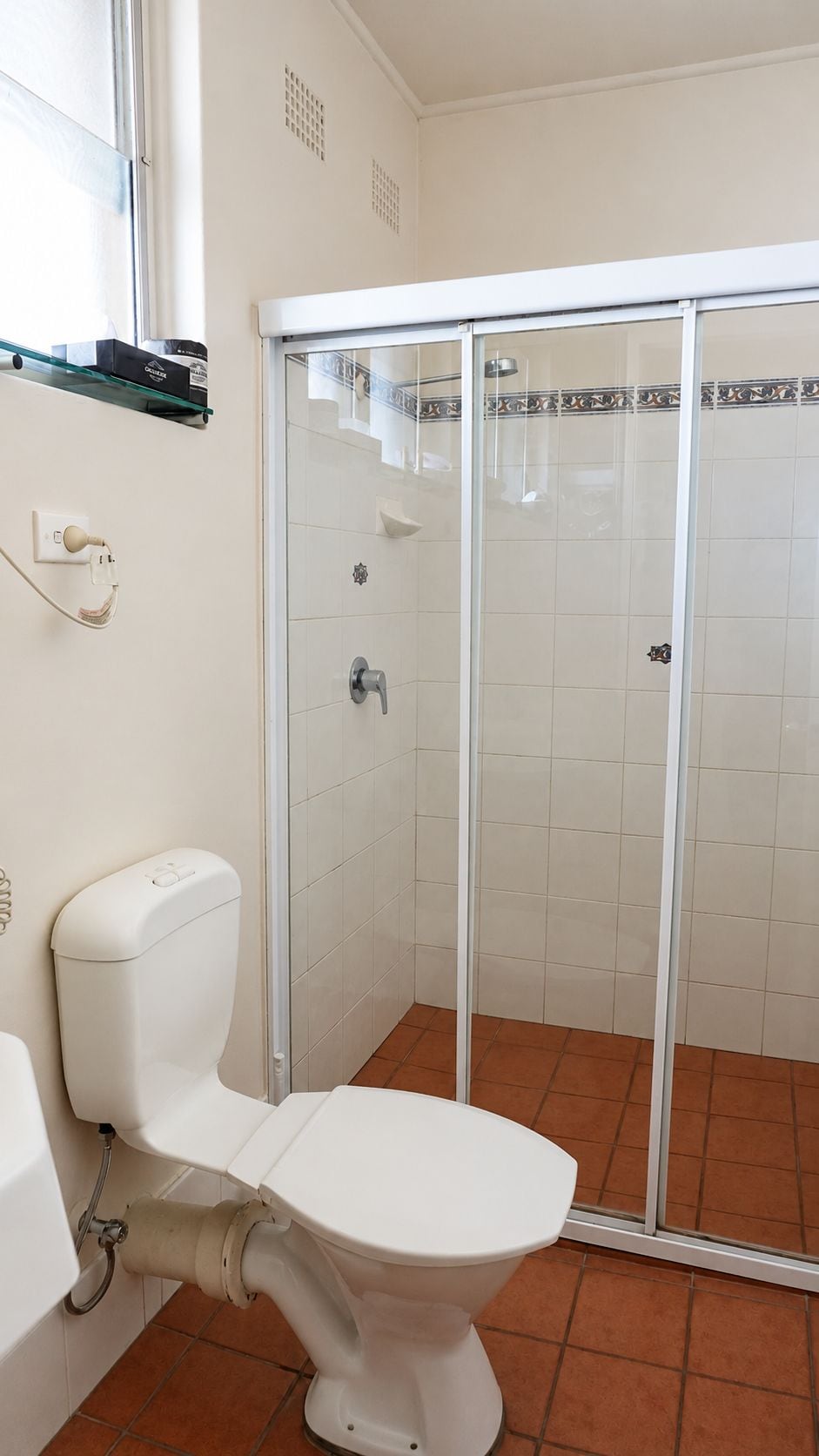 Ein Badezimmer mit Toilette, Duschkabine und Fenster.