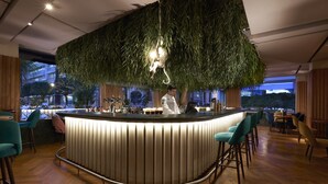 Un área de bar moderna con una barra curva, taburetes y una lámpara colgante.