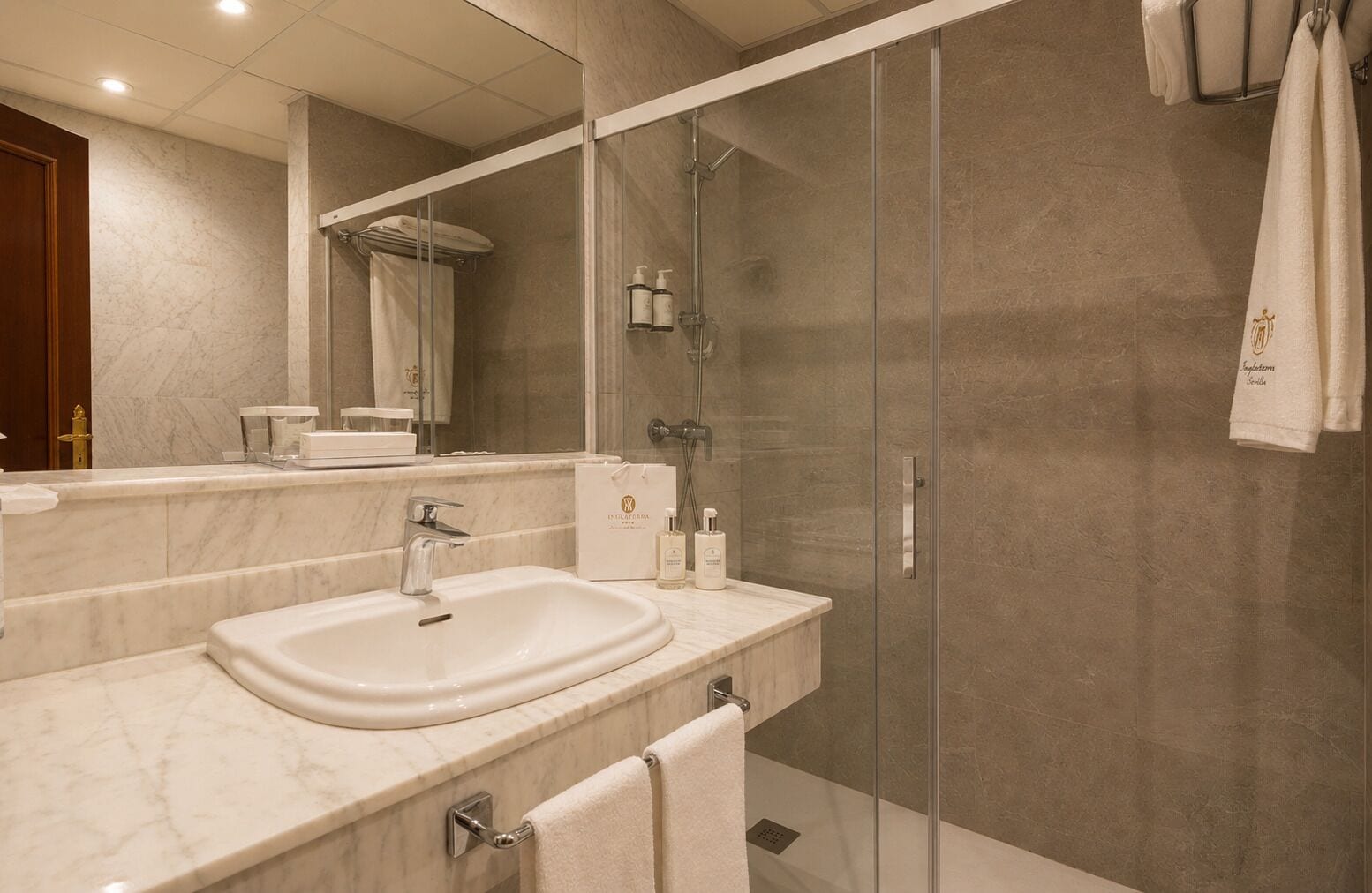 Un baño moderno con lavamanos doble, ducha con cerramiento de vidrio y un espejo grande.