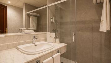 Un baño moderno con lavamanos doble, ducha con cerramiento de vidrio y un espejo grande.