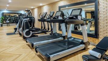 A gym with treadmills, exercise bikes, and a mirrored wall.