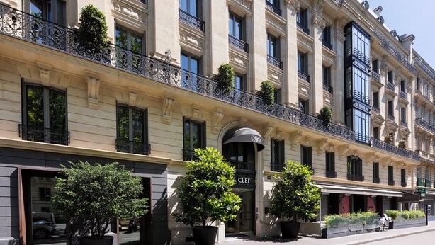 A historic building with ornate balconies, large windows, and potted plants. - La Clef Tour Eiffel Paris by The Crest Collection (Paris)
