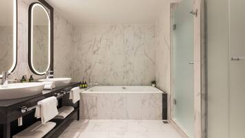 A modern bathroom with two sinks, a large bathtub, and a glass shower enclosure.