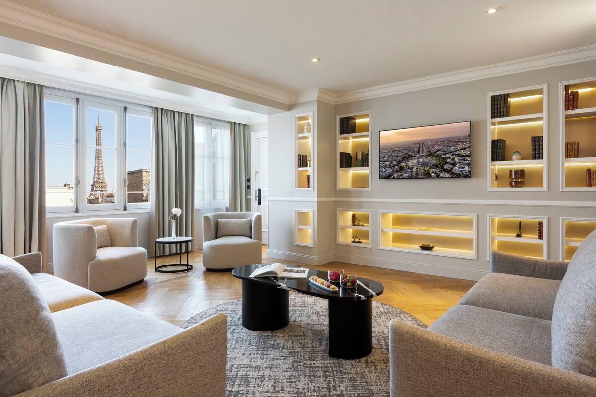 A modern living room with a view of the Eiffel Tower, a black coffee table, and built-in shelves with decorative items.