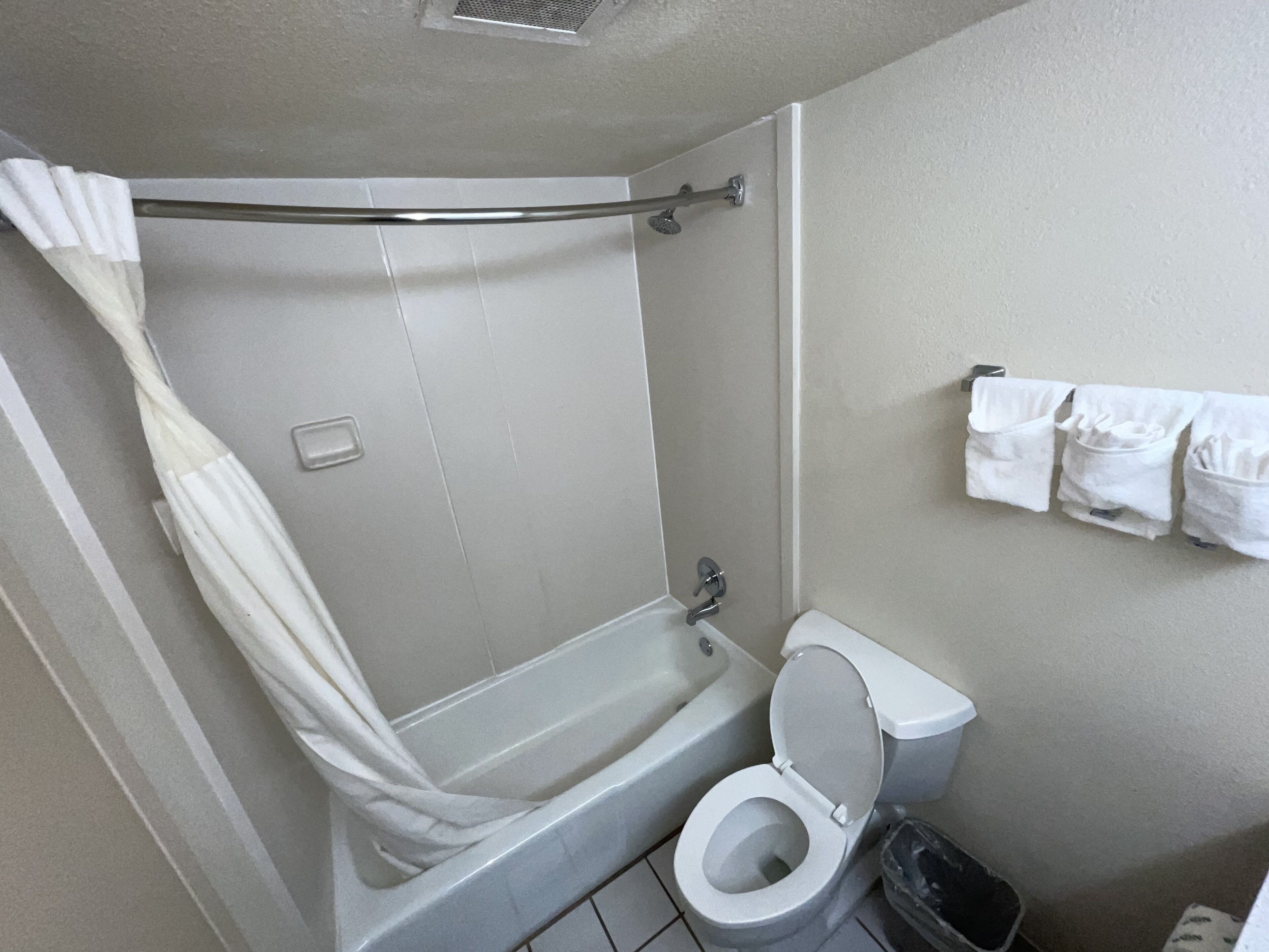 Un baño con ducha, inodoro y toallero.