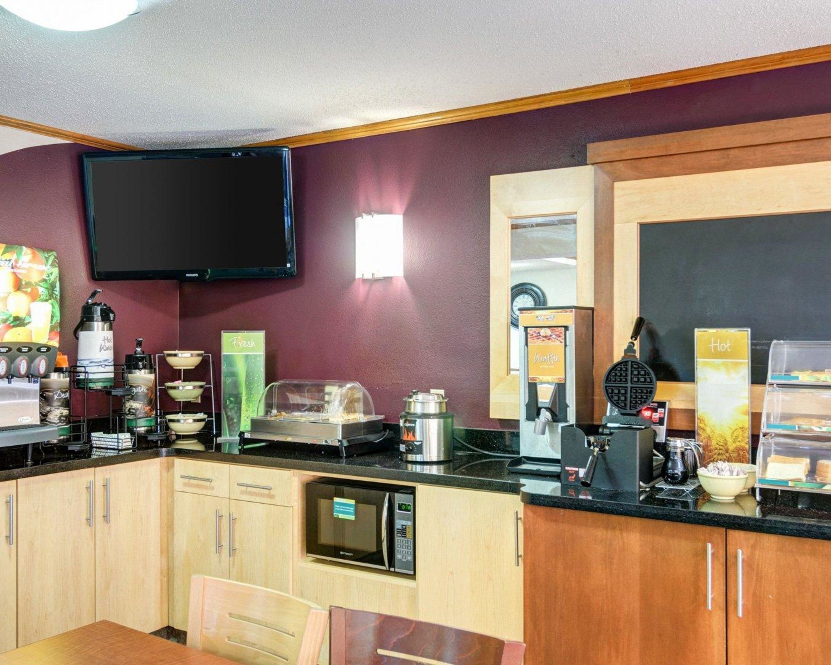 Une petite cuisine équipée d’un four à micro-ondes, d’une machine à café, d’un appareil à gaufres et de différents récipients pour aliments.
