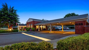 A hotel with a covered parking area, a brick facade, and a sign indicating a caution zone. - Best Western Lakewood (Lakewood)