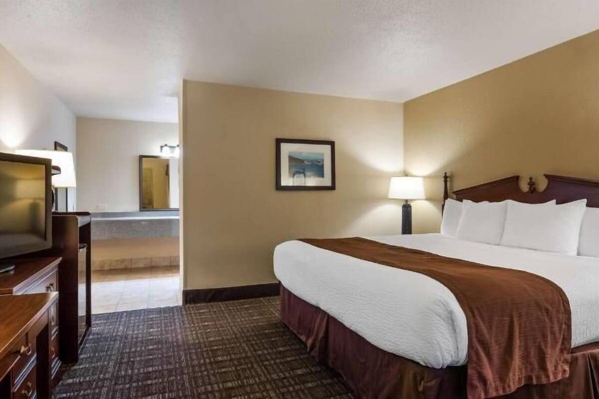 Een hotelkamer met een bed, een televisie, een bureau en een badkamer in de achtergrond.
