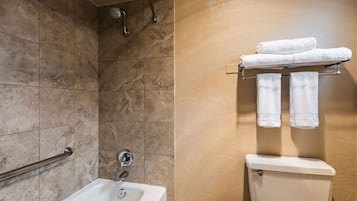A bathroom with a shower, a sink, and a toilet. There are two towels on a rack.