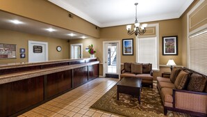 A reception area with a reception desk, a sofa, a coffee table, a chandelier, and a rug. - Best Western Lakewood (Lakewood)