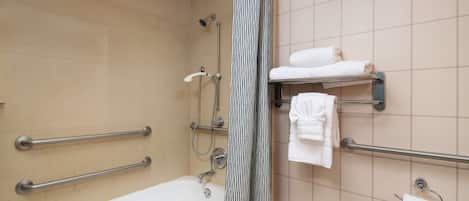 A bathroom with a bathtub, grab bars, a shower curtain, and a towel rack.