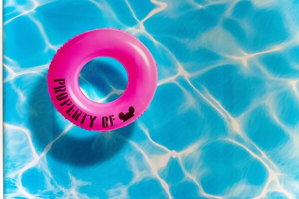 Un anneau gonflable rose avec l’inscription « APPARTIENT À » dans une piscine.