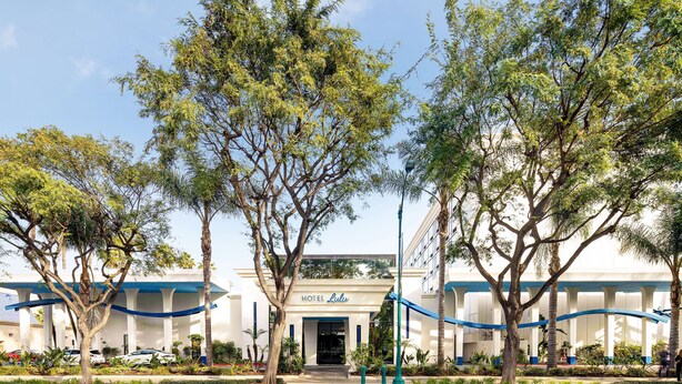 A hotel entrance with a covered walkway, trees, and a clear sky.