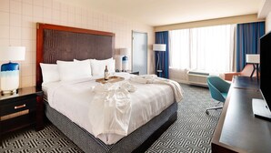 A hotel room with a large bed, a desk, a chair, and a TV.