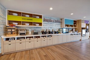 A modern kitchen with wooden cabinets, a countertop with various appliances, and a wall with a 'Good Morning' sign. - Home2Suites by Hilton Anaheim Resort (Anaheim)