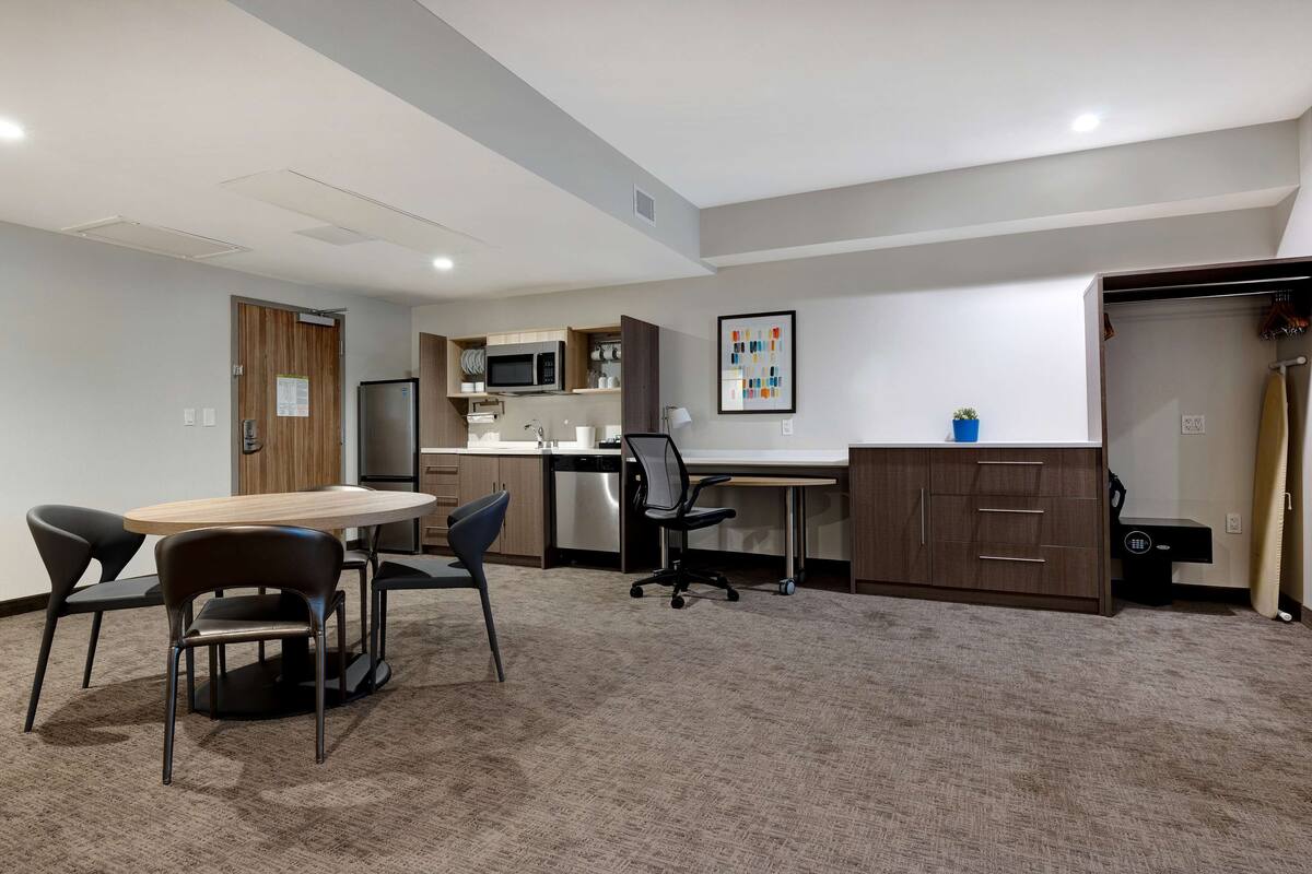 A modern kitchen with a microwave, stove, and cabinets. There is a dining area with a table and chairs.