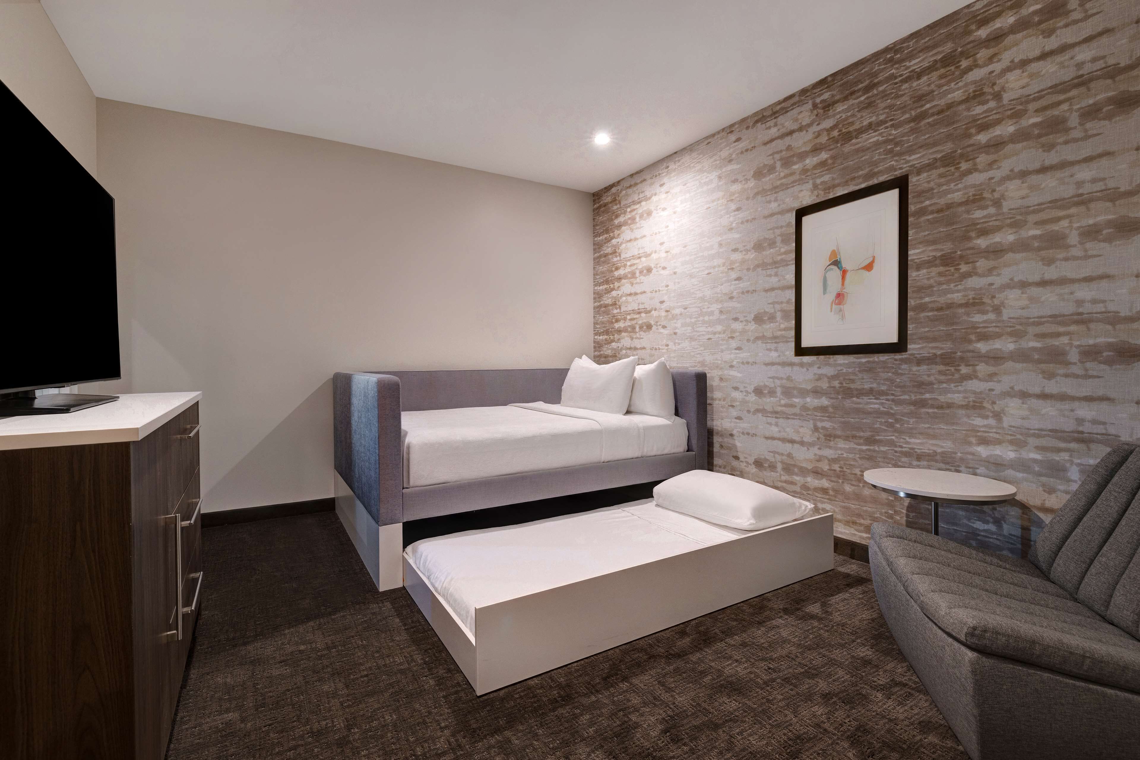A modern bedroom with a bunk bed, a desk, and a small round table.
