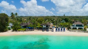 A beachfront property with multiple villas, a sandy beach, and clear turquoise waters. - The Sandpiper (Holetown)