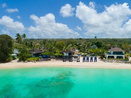 Una propiedad frente a la playa con varias villas, una playa de arena y aguas turquesas cristalinas.