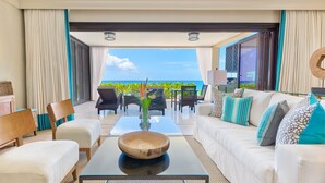 A modern living room with a glass coffee table, white sofa, and chairs, overlooking a scenic ocean view. - The Sandpiper (Holetown)