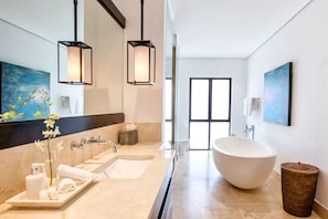 A modern bathroom with a large bathtub, dual sinks, and a vanity with toiletries.
