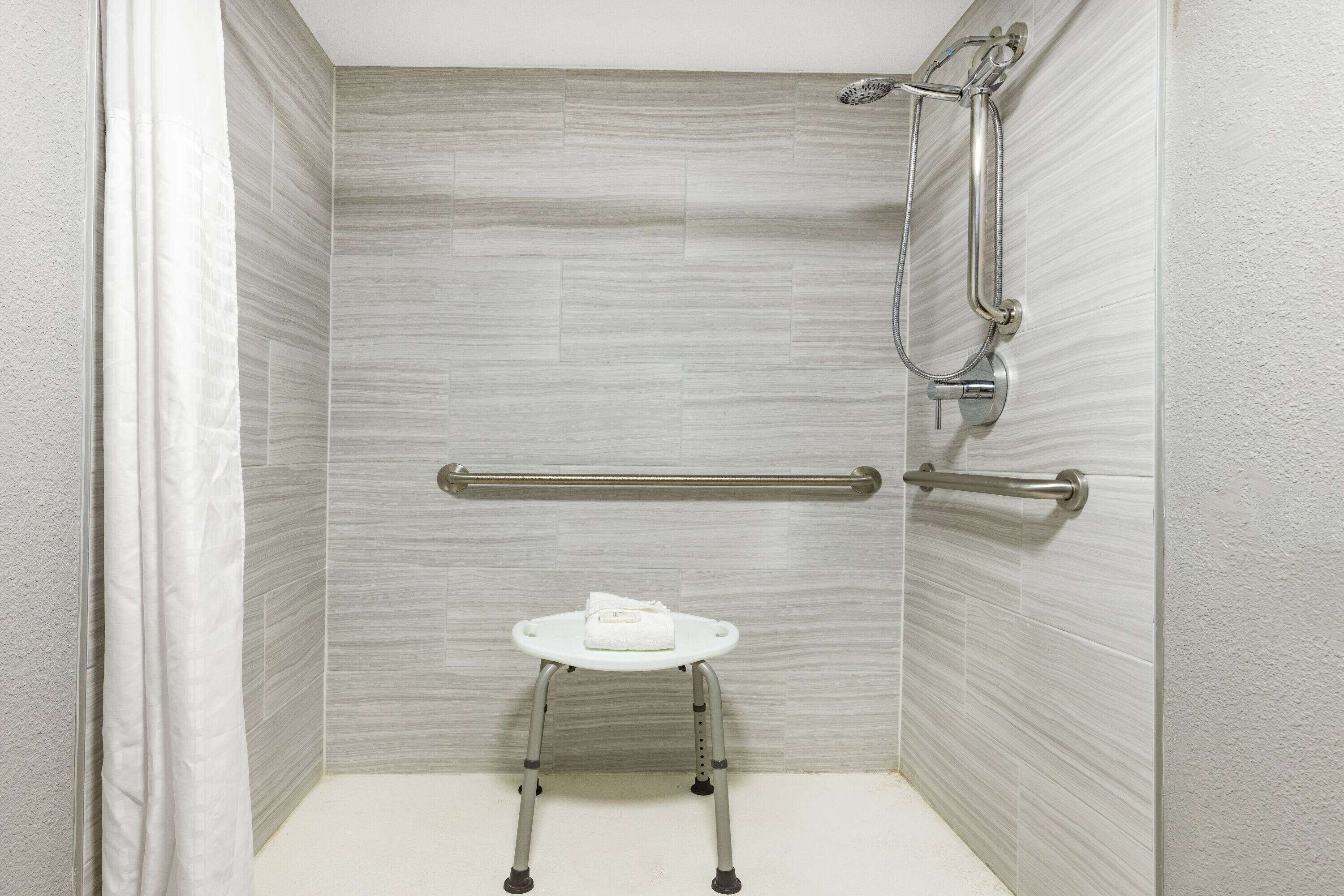 A shower area with a grab bar, a white toilet, and a showerhead.