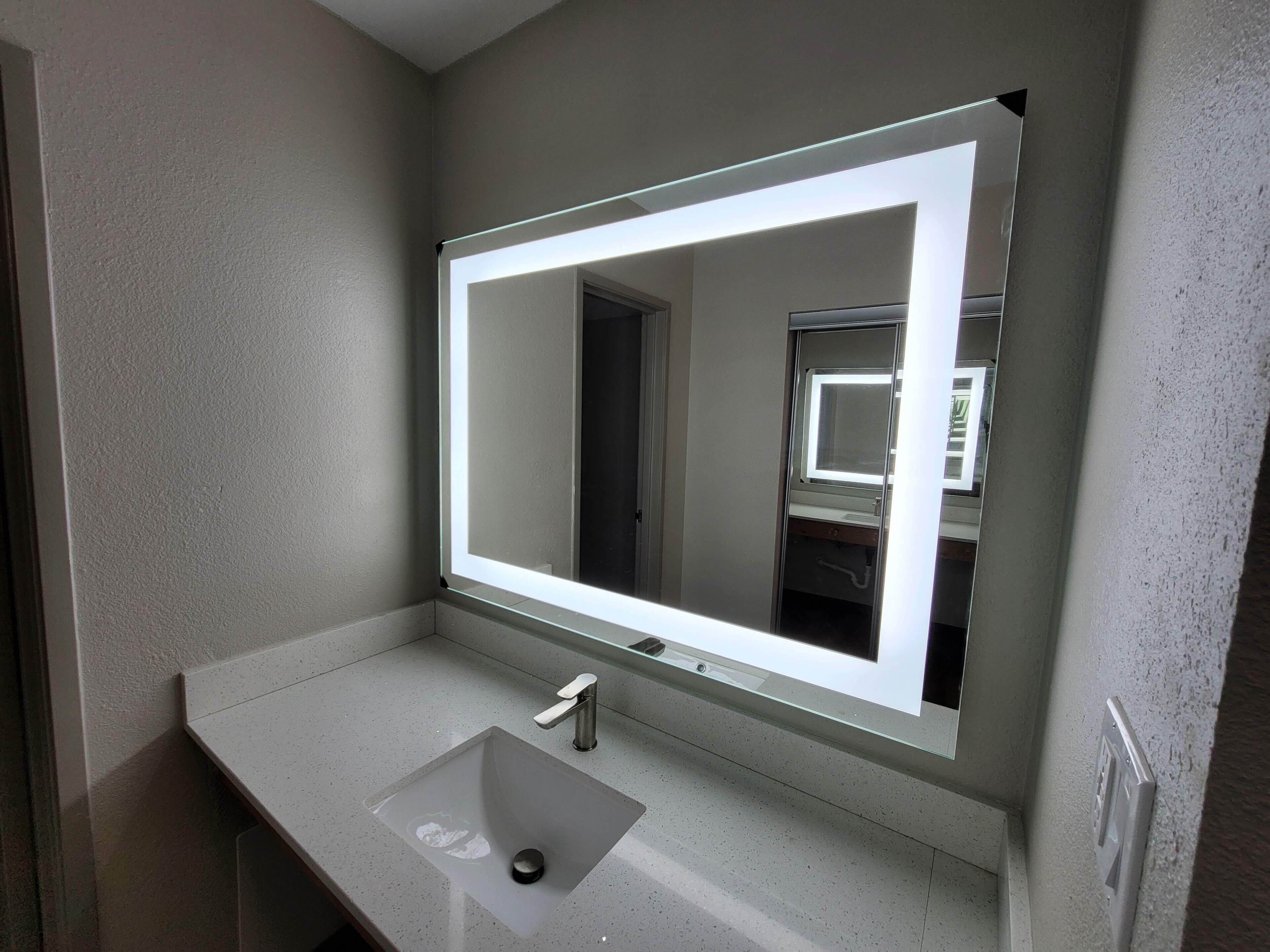 Een badkamer met een grote spiegel, een wastafel en een deur.