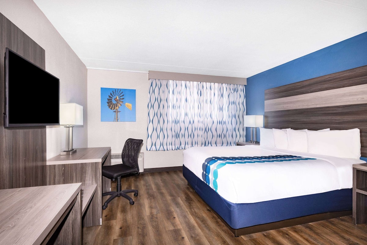 A hotel room with a bed, desk, chair, and a television.