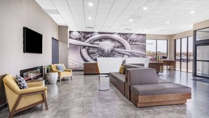 Eine moderne Lobby mit einer großen Wandmalerei, bequemen Sitzgelegenheiten und Blick auf den Parkplatz.