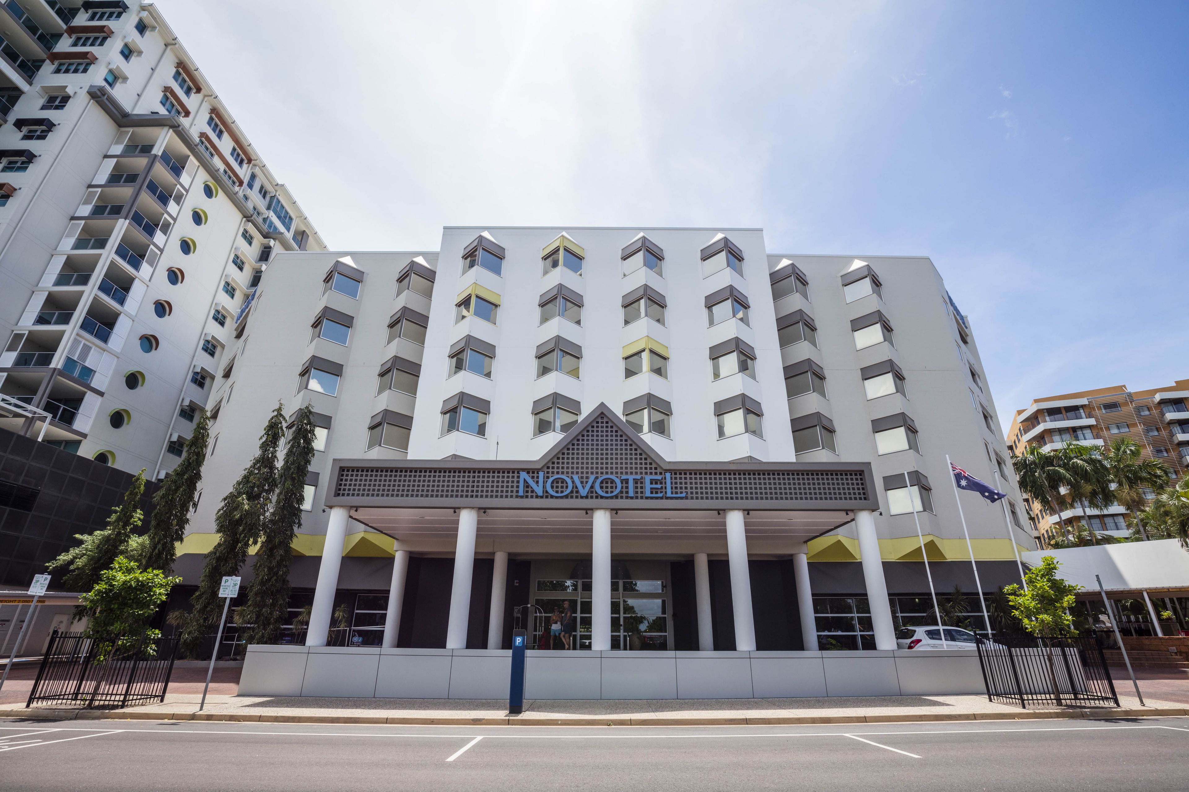 A modern hotel with a prominent 'NOVOTEL' sign, multiple floors, and a central entrance.
