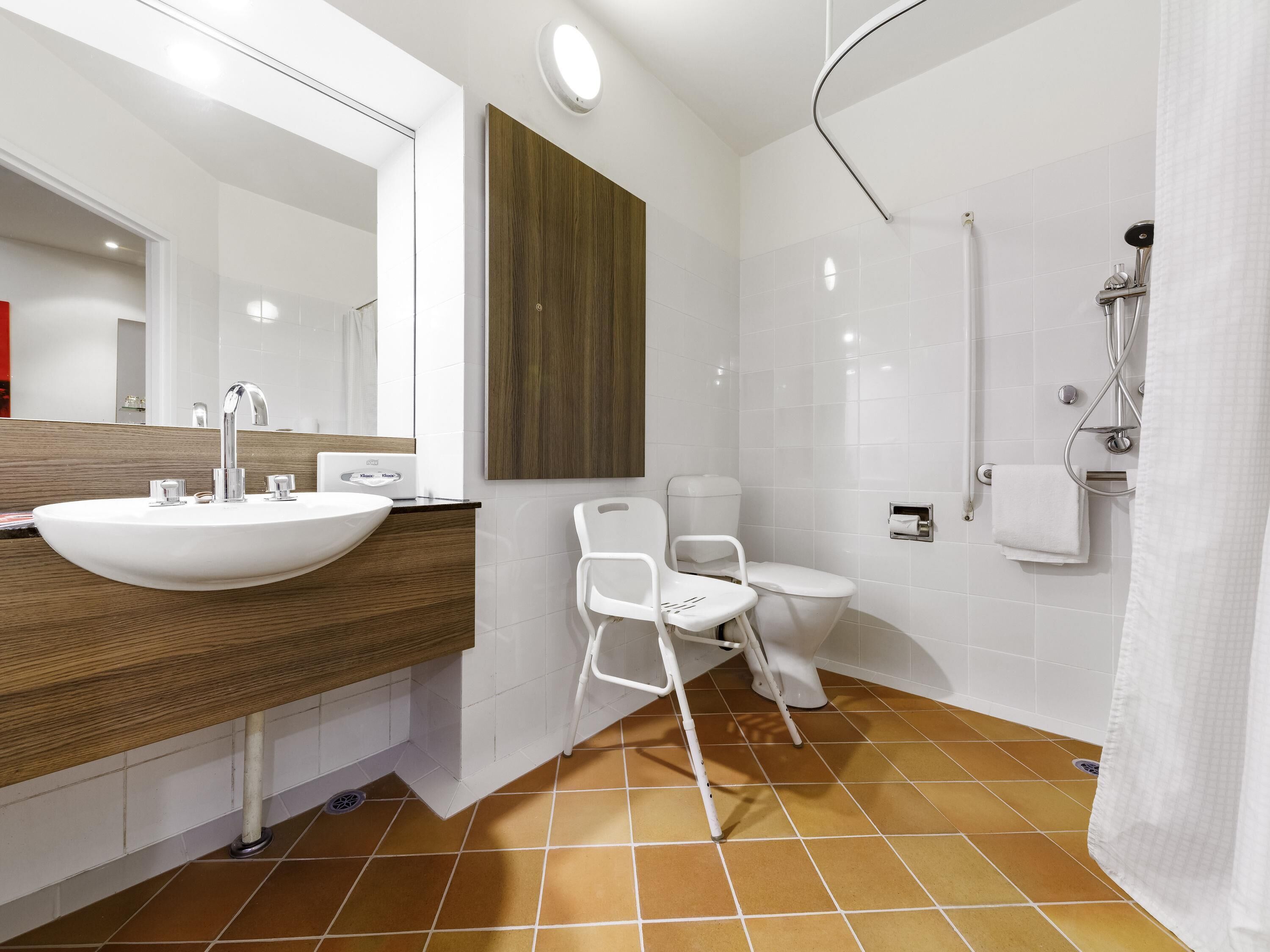 A modern bathroom with a large sink, mirror, and shower.