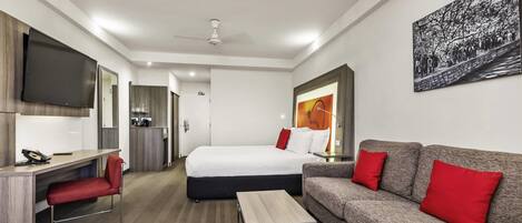 A modern hotel room with a bed, a sofa, a desk, and a television.