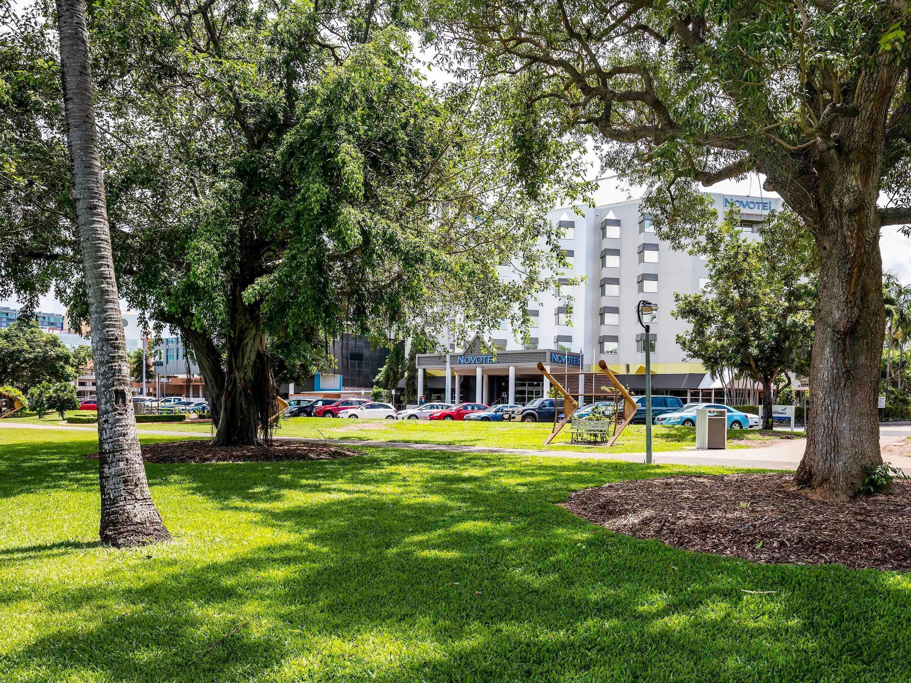 A hotel with a modern design, a parking area, and a well-maintained lawn.