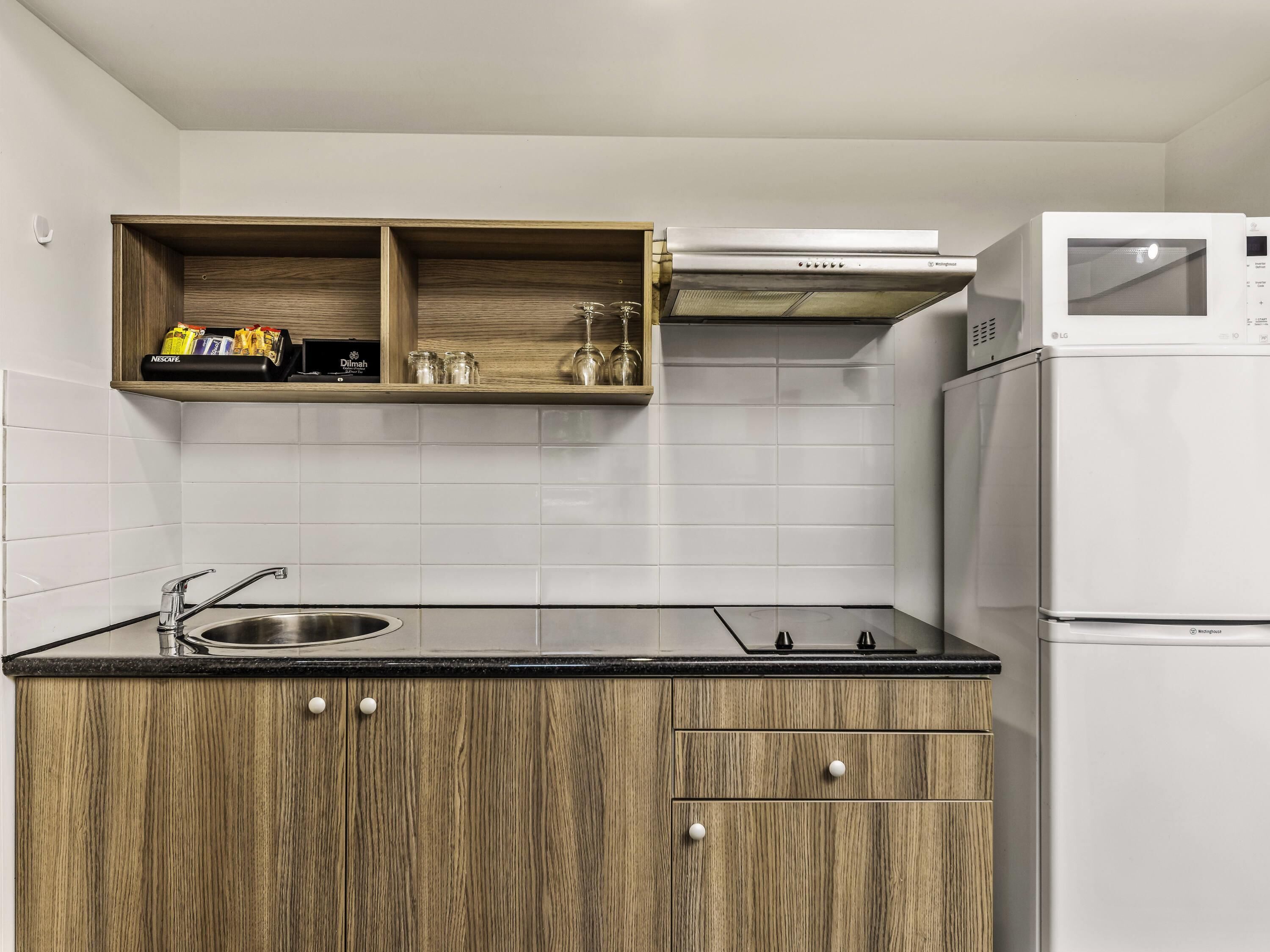 A kitchen with a stainless steel sink, wooden cabinets, a microwave, and a built-in oven.