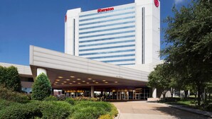 A Sheraton hotel with a modern design, featuring a large entrance and a clear sky. - Sheraton Arlington (Arlington)