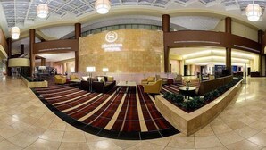 A spacious lobby with a checkered carpet, multiple seating areas, and a prominent reception desk. - Sheraton Arlington (Arlington)