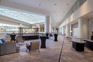 A spacious lobby with a high ceiling, large windows, and modern furniture. - Sheraton Arlington (Arlington)