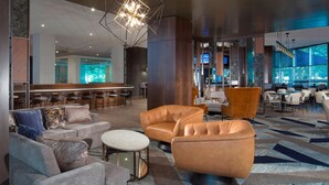 A modern lobby with leather sofas, a bar area, and a large geometric chandelier. - Sheraton Arlington (Arlington)