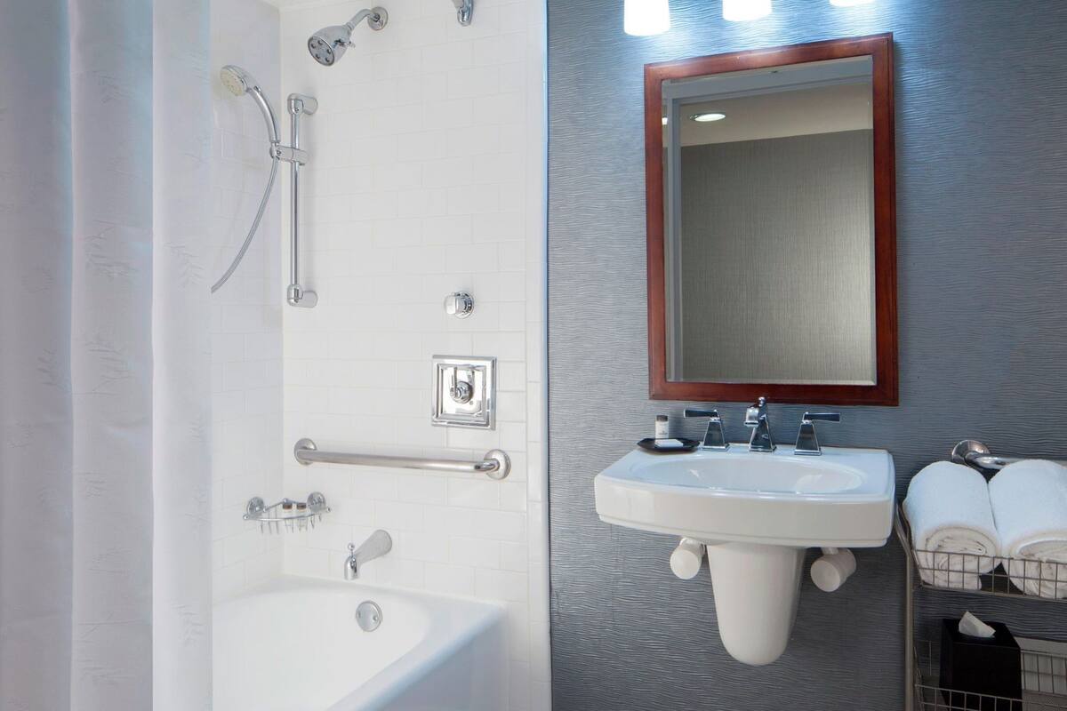 A bathroom with a bathtub, a shower, a sink, and a mirror.