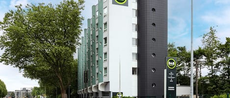 Un hotel tipo bed and breakfast de diseño moderno, con una destacada torre cilíndrica y una fachada plana con amplias ventanas.