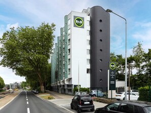 Un hôtel de type « bed and breakfast » au design moderne, caractérisé par une imposante tour cylindrique et une façade plate dotée de nombreuses fenêtres.