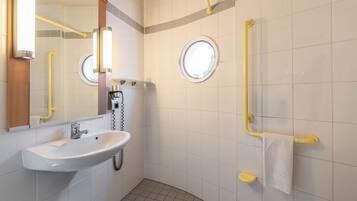 Ein modernes Badezimmer mit Waschbecken, Spiegel und zwei Haltegriffen.