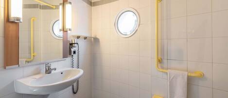 A modern bathroom with a sink, mirror, and two grab bars.