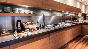 A modern kitchen with wooden cabinets, a stainless steel countertop, and various breakfast items.