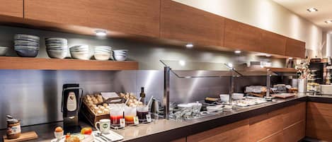 Una cocina moderna con armarios de madera, encimera de acero inoxidable y diversos alimentos para el desayuno.