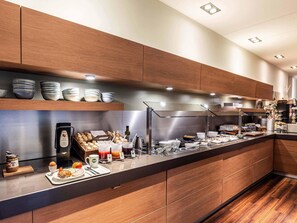 Une cuisine moderne avec des meubles en bois, un plan de travail en acier inoxydable et divers aliments pour le petit-déjeuner.