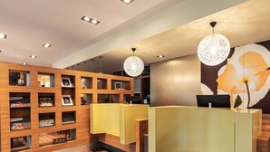 A reception area with wooden shelving displaying magazines, a reception desk, and a large floral mural on the wall.