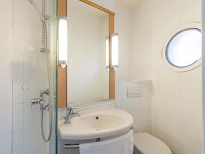 Ein modernes Badezimmer mit einer gläsernen Dusche, einem weißen Waschbecken und einer Toilette.
